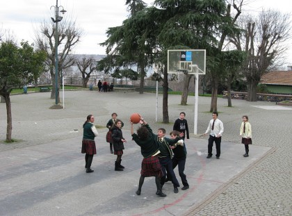 School children playing basket ball in a school yard